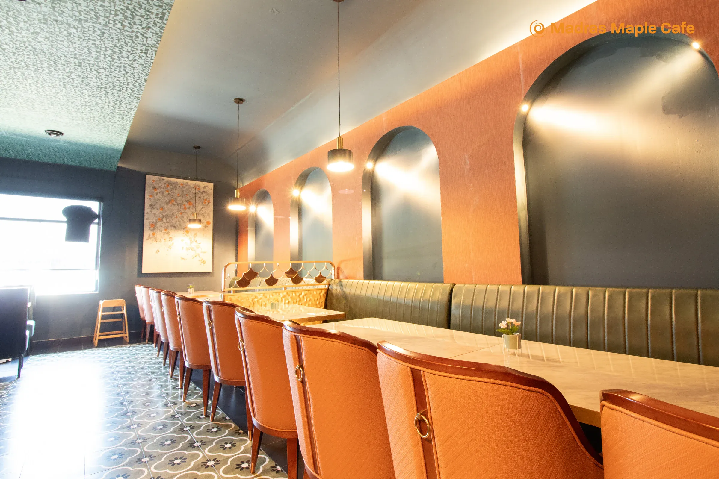 Madras Maple Cafe booth seating beneath arched mirrors and warm pendant lights