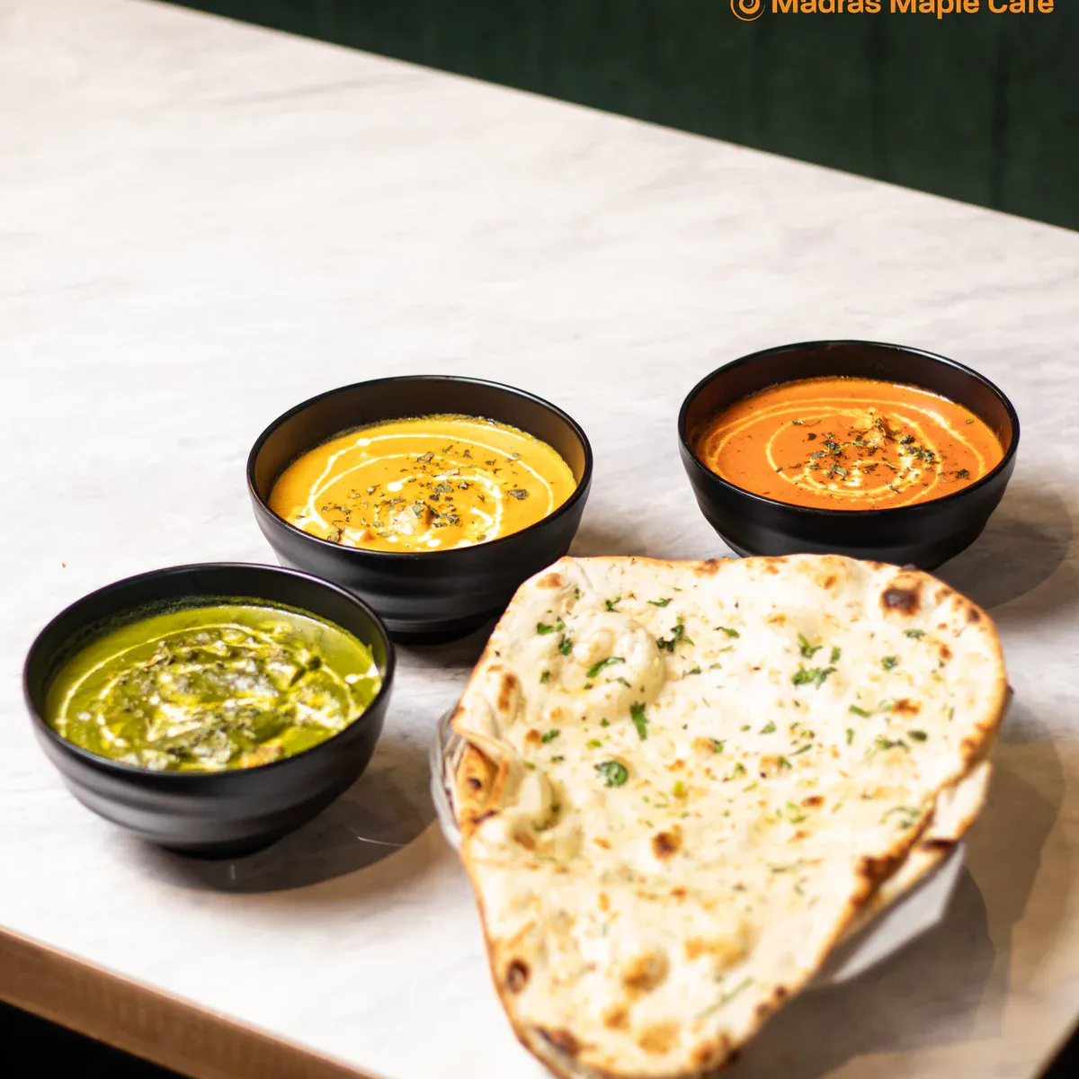 Butter chicken served with rice, naan, and a side.